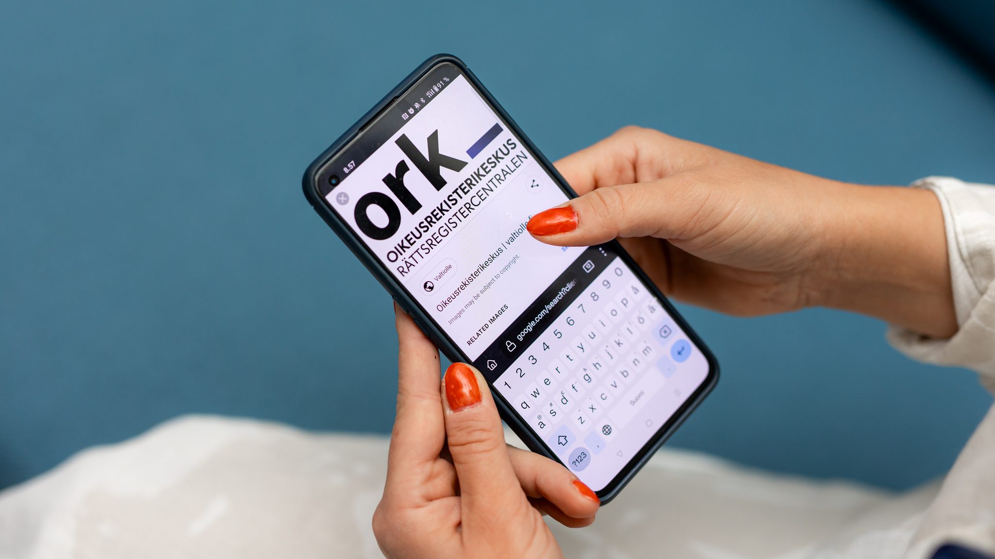 A person is holding a smartphone with the Legal Register Centre's website open. The screen shows the text "ork" and a search field below it.